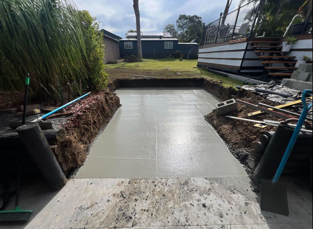 Fresh patio slab poured in an excavated backyard