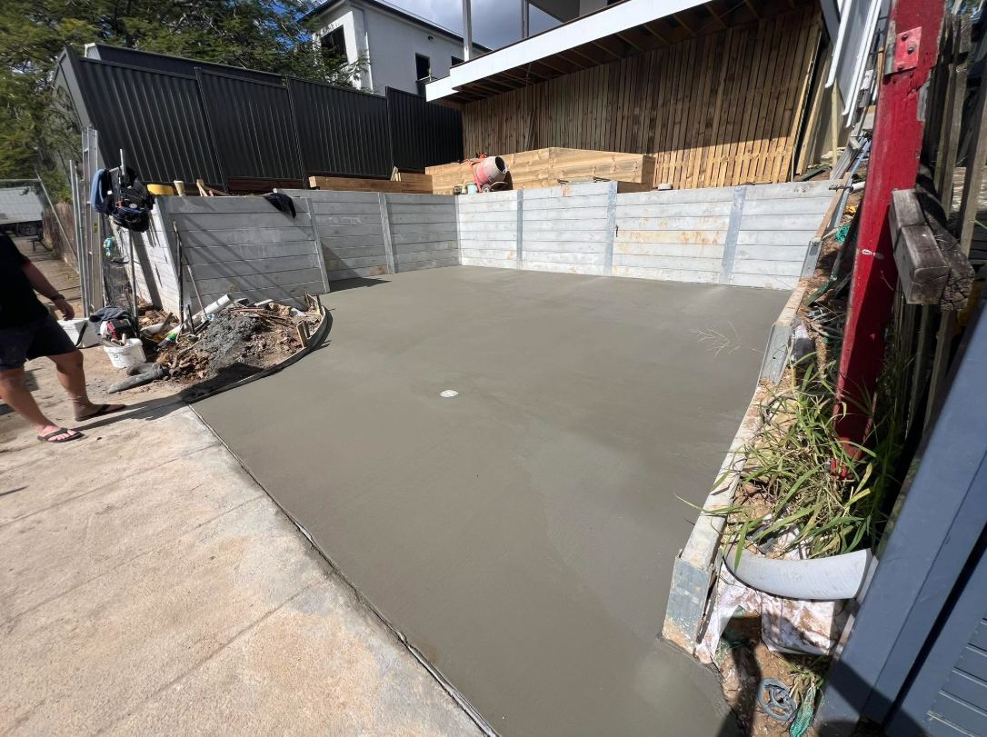Finished backyard slab between concrete sleeper walls