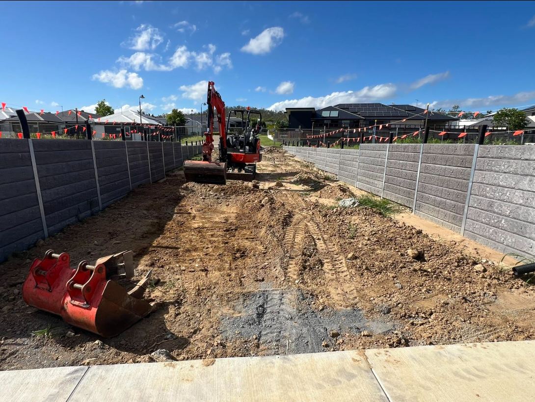 Excavator performing a site cut between retaining walls
